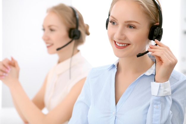 Call center. Concentrarsi sulla bella donna bionda in cuffia.