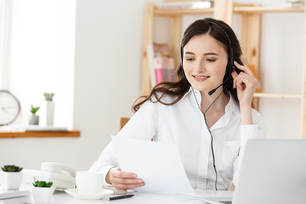 Call Center Concept: Ritratto di felice sorridente operatore telefonico di assistenza clienti femminile sul posto di lavoro.