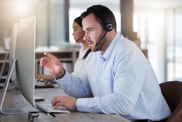 Call center consulenza e computer con uomo in ufficio per comunicazione servizio clienti o help desk Telemarketing vendite e consulenza con dipendente maschio per impegno contattaci e hotline