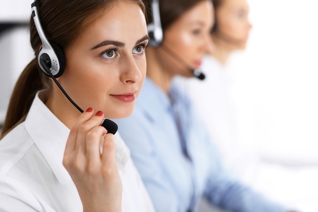 Call center. Gruppo di operatori al lavoro. Concentrarsi sulla bella donna d'affari in cuffia.