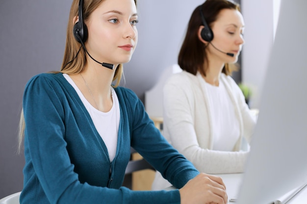 Call center Gruppo di operatori al lavoro Concentrati sulla receptionist donna in cuffia al servizio clienti