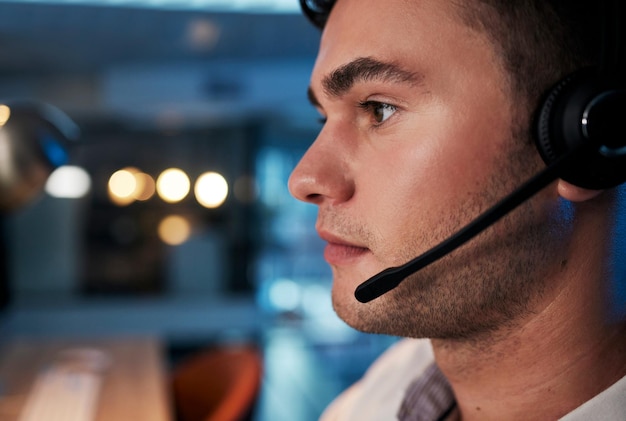 Call center notte e volto dell'uomo con microfono per consulenza per il servizio clienti telemarketing e vendite in un ufficio Uomo che lavora in CRM contattaci e attività di telecomunicazioni per supporto e aiuto