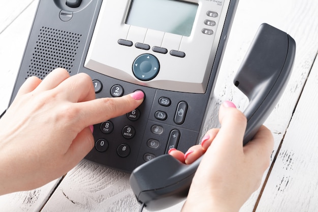 Call center o ufficio telefono concetto, dito femminile premere il numero sul pad del telefono