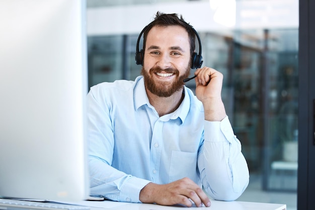 Call center uomo felice e sorriso ritratto nel supporto del servizio clienti o telemarketing in ufficio Consulente o agente di affari amichevole sorridente in consulenza online o assistente virtuale sul posto di lavoro