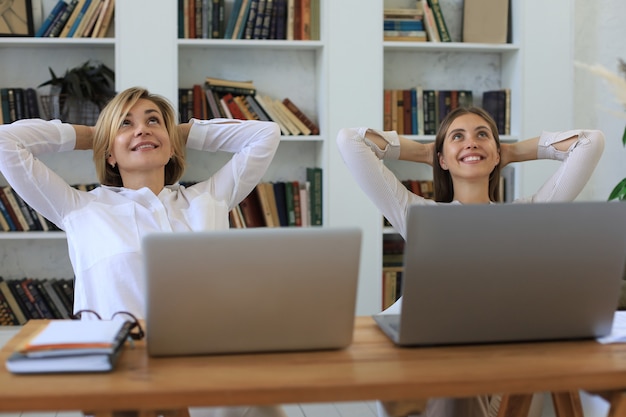 Calma donna d'affari sorridente che si rilassa su una comoda sedia da ufficio con le mani dietro la testa, donna felice che riposa in ufficio soddisfatta dopo il lavoro svolto, godendosi la pausa con gli occhi chiusi, la pace della mente, senza stress.