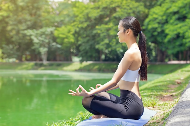 Calma e relax, le donne asiatiche meditano mentre praticano lo yoga nel parco all'aperto. concetto di libertà felicità della donna. immagine tonica vita sana