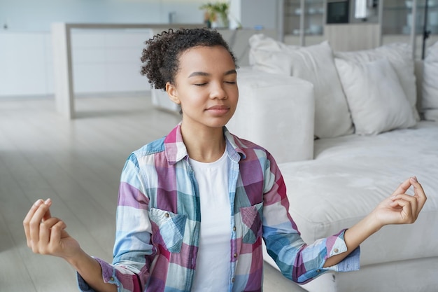 Calma ragazza di razza mista medita per alleviare lo stress fa esercizi di respirazione con il gesto di mudra a casa