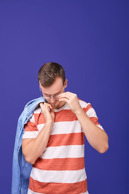 Calmo bell'uomo tiene la camicia di jeans con la mano