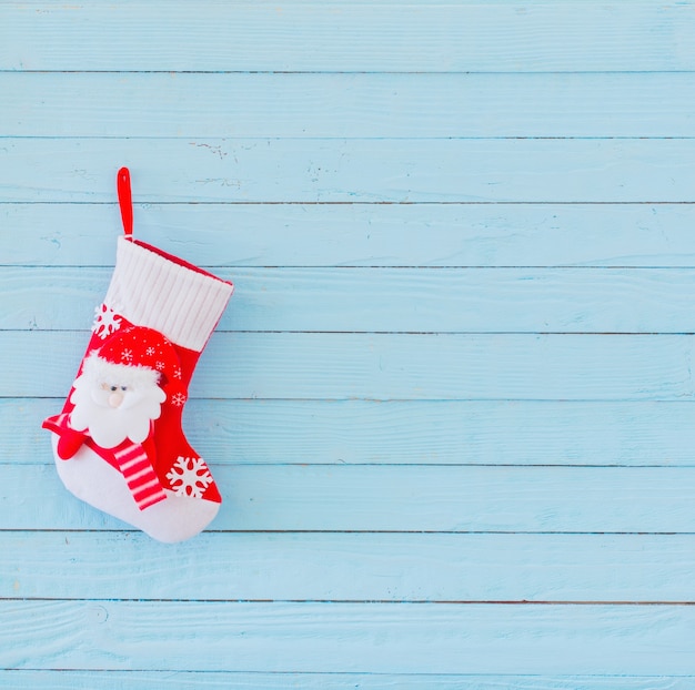 Calza di Natale con doni che appendono sul legno blu