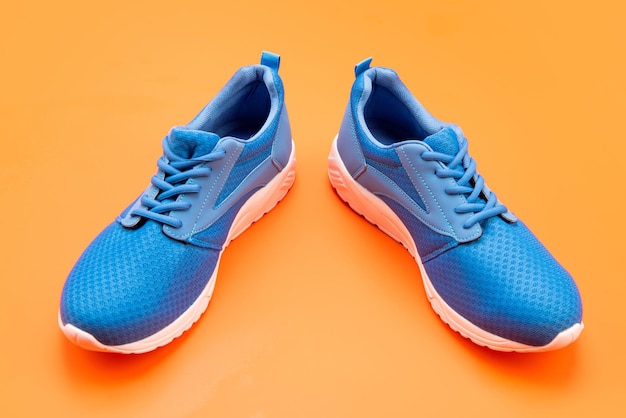 Calzature di concetto di acquisto per l'allenamento calzature atletiche per la corsa paio di comode scarpe sportive scarpe da ginnastica blu sportive su sfondo arancione negozio di scarpe