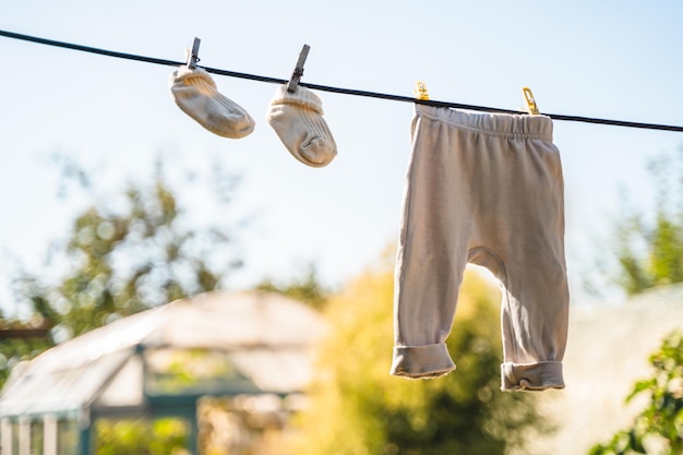 Calzini e pantaloni per neonati sono appesi a una corda con mollette su uno sfondo