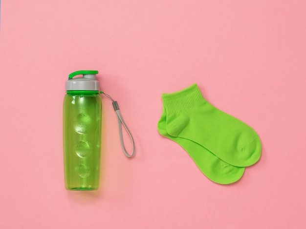 Calzini sportivi verdi e una bottiglia d'acqua verde su sfondo rosso Accessori sportivi Posa piatta