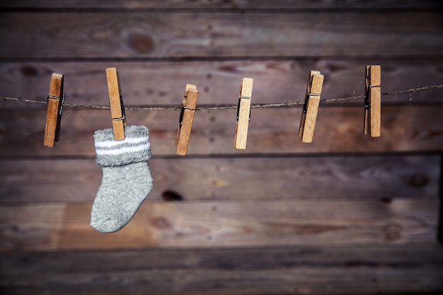 Calzino grigio con una molletta da bucato su una parete di legno