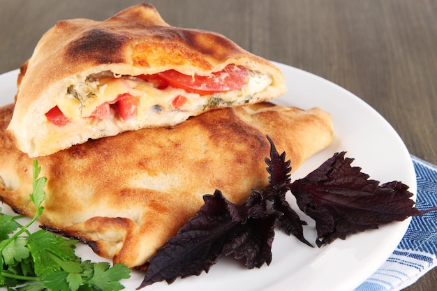 Calzone della pizza sul piatto sul tovagliolo sulla tavola di legno