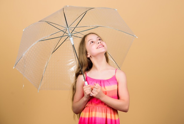 Cambiamenti stagionali. Stagione autunnale. Godetevi il concetto di pioggia. Accessorio impermeabile. Giorni di pioggia in arrivo. Adoro i giorni di pioggia. Ombrello trasparente della tenuta felice della ragazza del bambino. Goditi il tempo piovoso. Protezione invisibile.