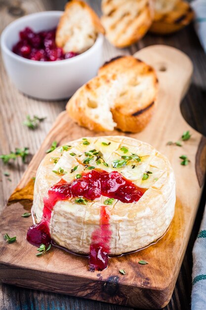 Camembert al forno con salsa di mirtilli rossi e timo su tavola di legno rustica