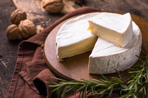 Camembert dell'azienda agricola biologica o formaggio brie su una tavola di legno con rosmarino e noci, miele.