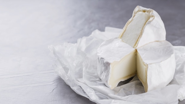 Camembert su fondo grigio cemento. Formaggio a pasta molle con muffa bianca su carta pergamena. Copia spazio. Vista dall'alto