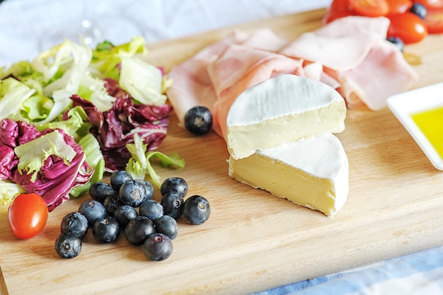 Camembert su un tagliere con carne di verdure e frutti di bosco