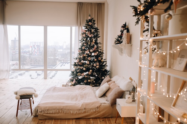 Camera da letto calda e accogliente con una grande finestra e un albero di Natale decorato