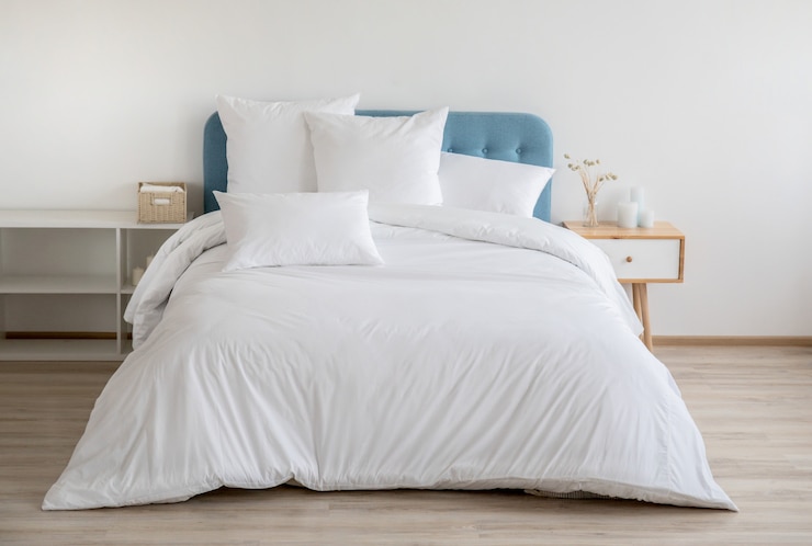 Foto camera da letto con letto, biancheria da letto bianca e comodino.