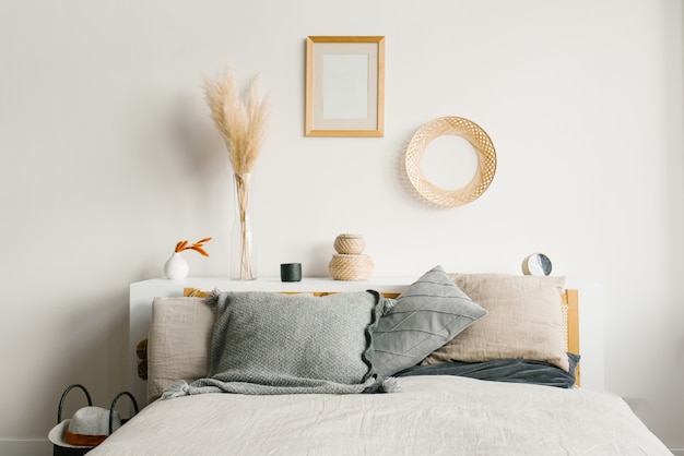 camera da letto in stile scandinavo minimalista naturale. Cuscini grigi sul letto. Decor sopra il letto