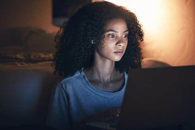 Camera da letto portatile e donna su internet di notte per sito web social media online o lavoro remoto a casa Computer da letto o persona africana seria in streaming film o video su tecnologia pc con insonnia