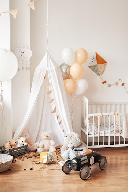 Camera per bambini, camera da letto, asilo nido in stile scandinavo bianco. Lettino con baldacchino. Scaffali e giocattoli in legno. Tenda a baldacchino, aquilone in tessuto e palloncini.