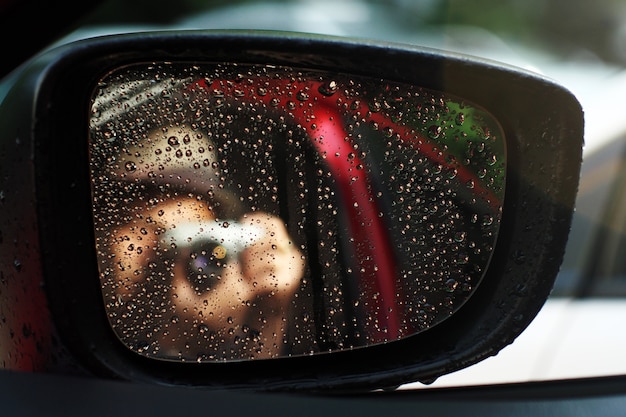 Cameraman e Gocce di pioggia viste attraverso lo specchietto retrovisore di un&#39;automobile