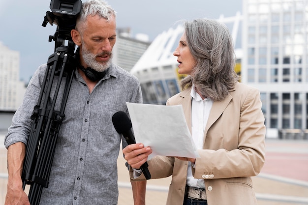 Cameraman maschio che parla con una giornalista donna