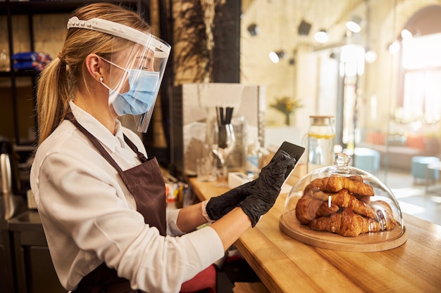 Cameriera al bancone del bar utilizzando un dispositivo moderno