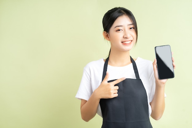 Cameriera asiatica che tiene il suo telefono con una faccia allegra