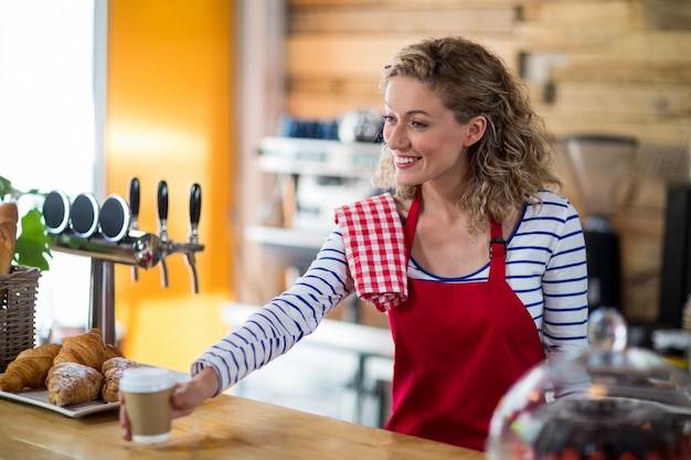 Cameriera che serve una tazza di caffè al cliente nel caffè