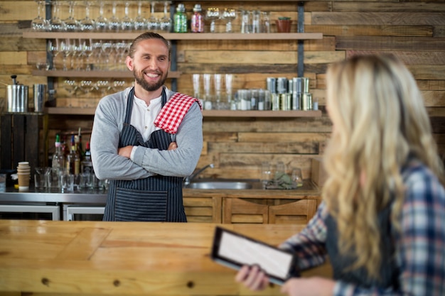 Cameriera di bar e cameriere sorridenti che interagiscono al contatore