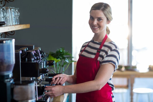 Cameriera di bar sorridente che produce tazza di caffè in caffetteria