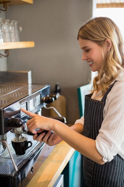 Cameriera di bar sorridente che produce tazza di caffè