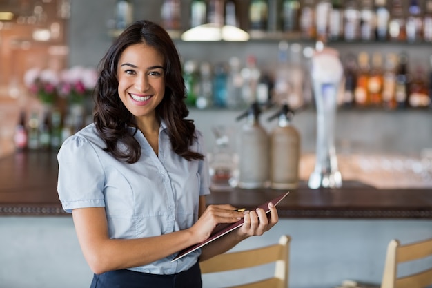 Cameriera di bar sorridente che tiene un blocco note