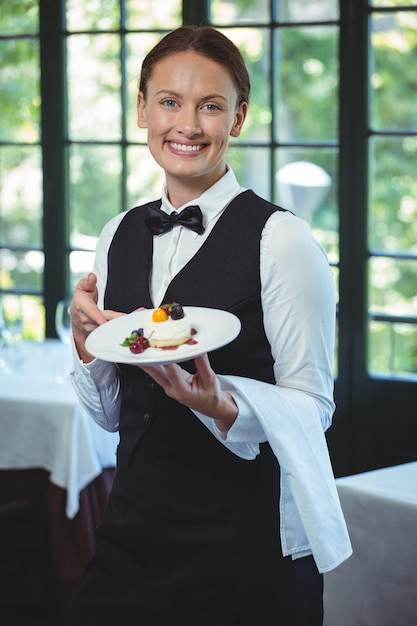 Cameriera di bar sorridente che tiene un piatto