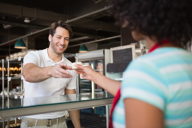 Cameriera dietro il bancone che dà la torta al cliente