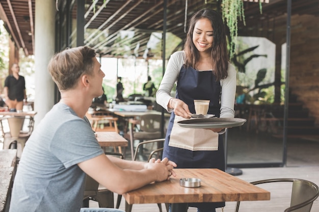 cameriera femminile che serve caffè a un cliente maschio