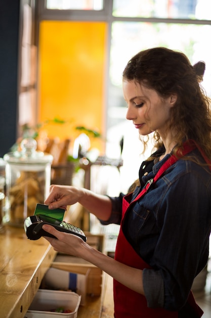 Cameriera scorrendo la carta di credito tramite il lettore di carte di credito al bancone