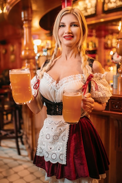 Cameriera sexy in uniforme retrò tiene boccali di birra