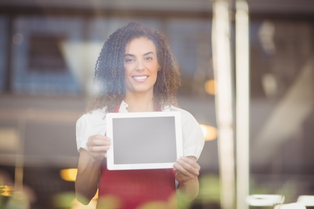 Cameriera sorridente che mostra una compressa digitale