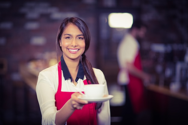 Cameriera sorridente che passa una tazza di caffè