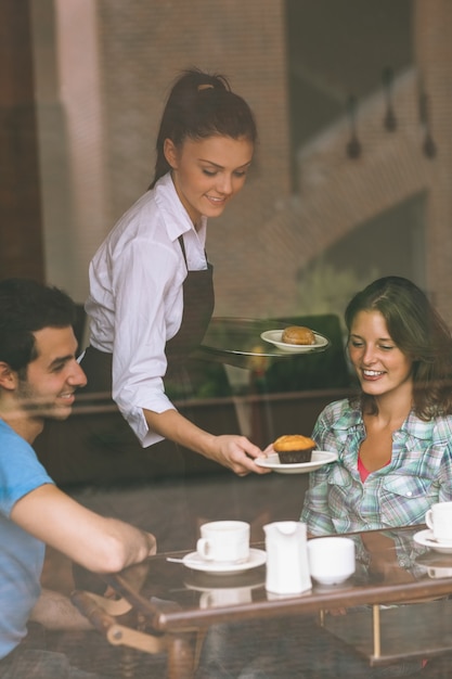 Cameriera sorridente che serve cibo a una coppia