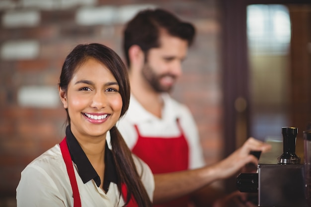 Cameriera sorridente che utilizza la macchina per il caffè