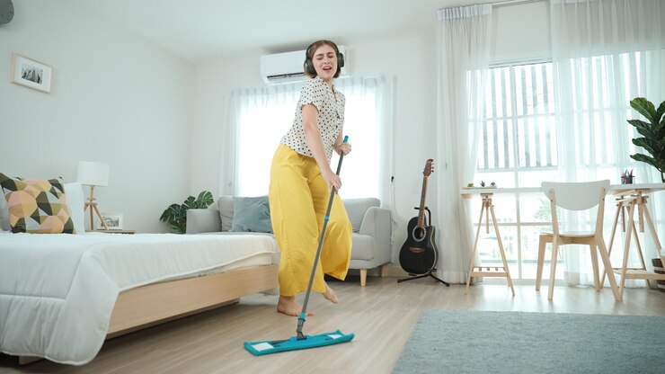 Foto cameriera sorridente con le cuffie ascolta musica mentre pulisce il pavimento pedagogia