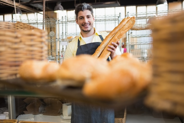 Cameriere allegro che tiene due baguette