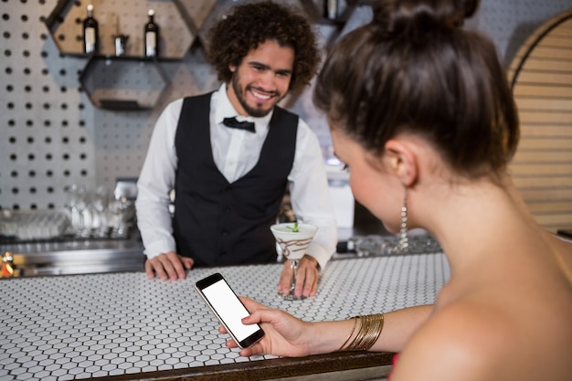 Cameriere che interagisce con la bella donna mentre si utilizza il telefono cellulare