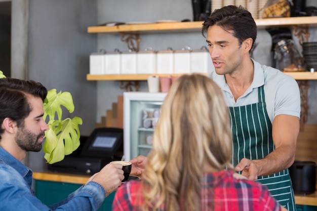 Cameriere che offre caffè a una coppia